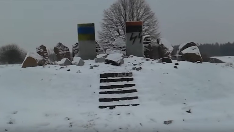 The partially destroyed monument to Polish villagers who were massacred in 1944 was painted in the colors of the Ukrainian and UPA flag. Photo: youtube screengrab. ~