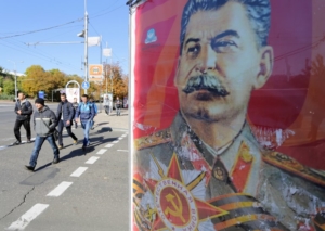 Фото снято 17 октября 2015 года в Донецке. Люди идут мимо портрета советского диктатора Иосифа Сталина, изображенного на рекламном постере. Фото AFP/Scanpix/Leta